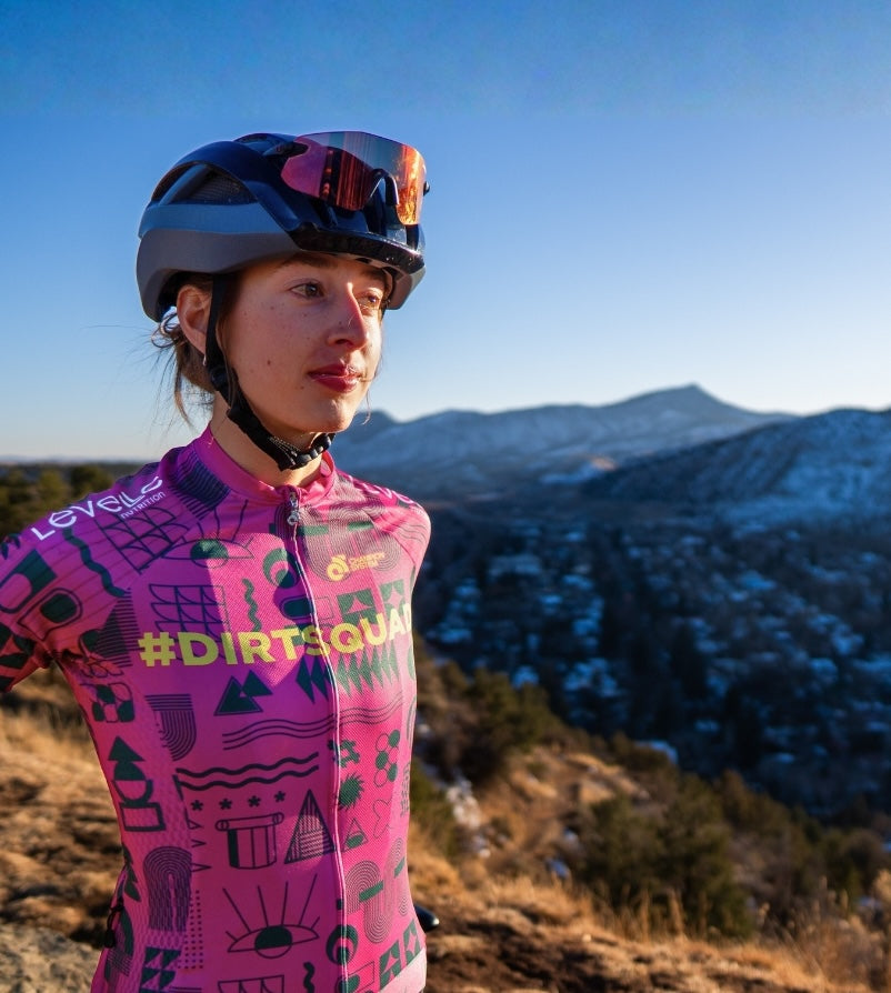 Person wearing a pink cycling jersey with mountainous landscape in the background